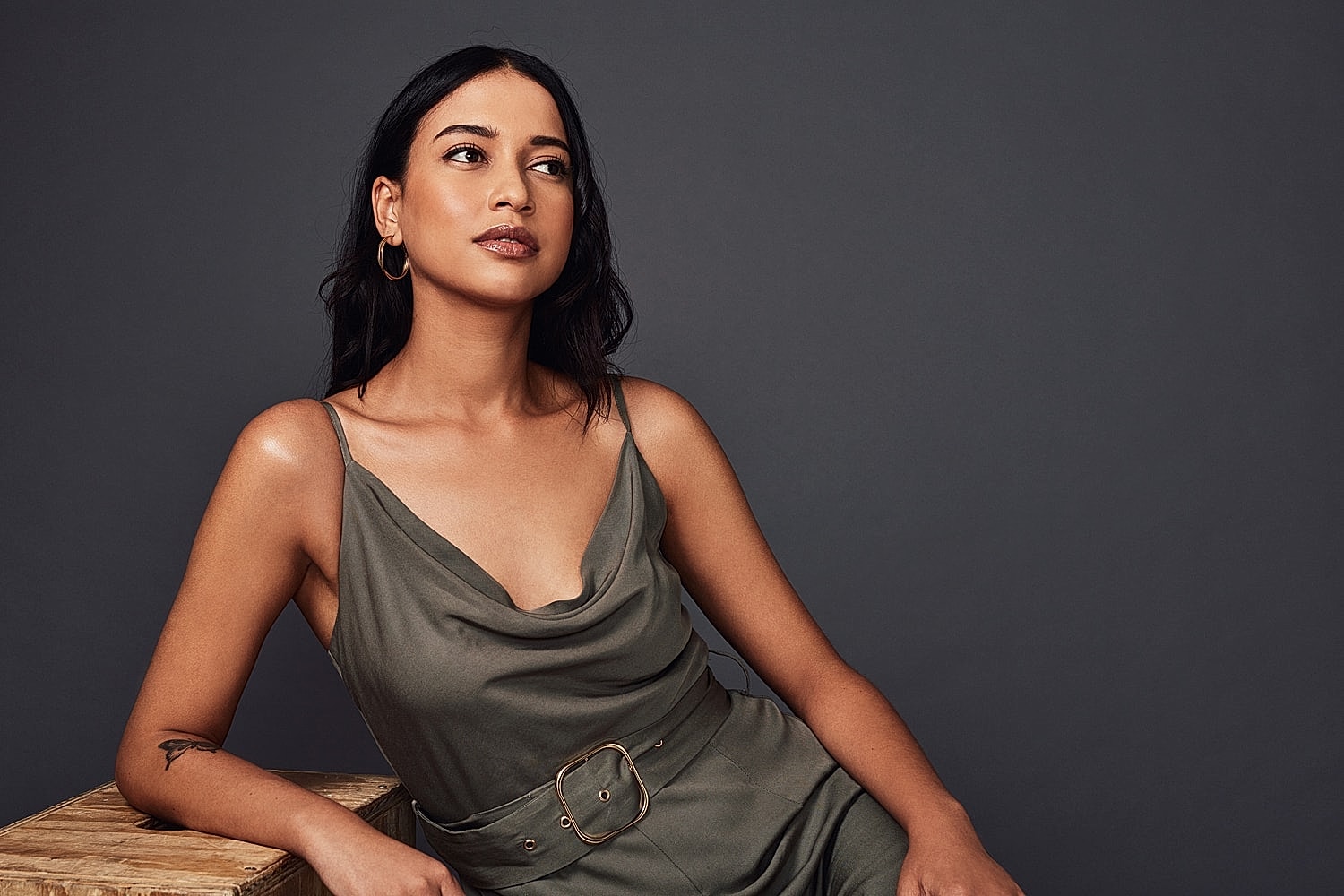 Woman in olive dress against dark background.