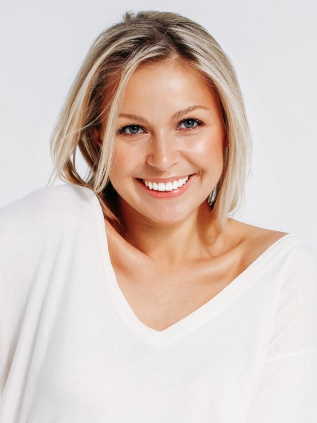 Smiling woman with light blonde hair and white shirt.