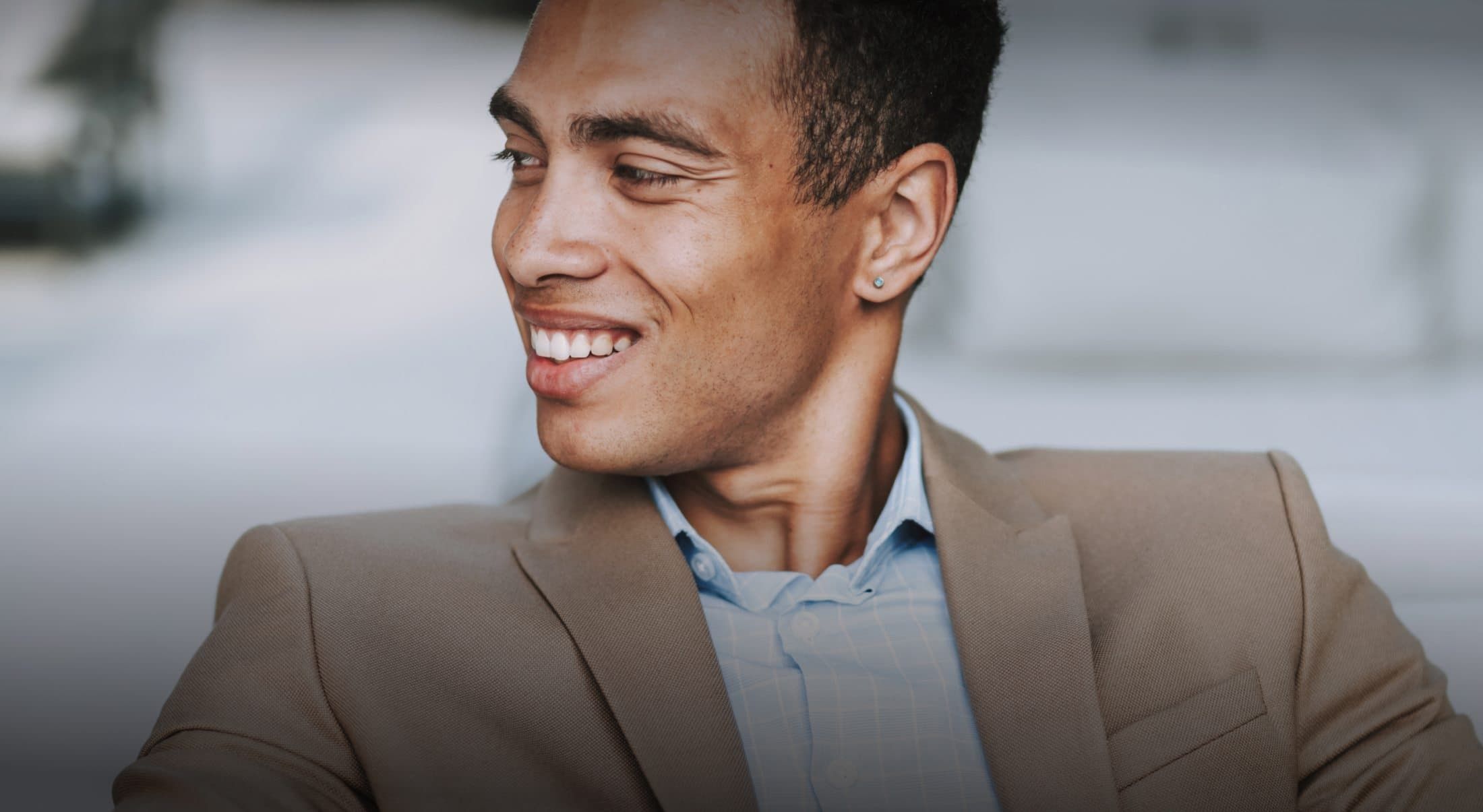 Smiling man wearing a tan suit jacket.