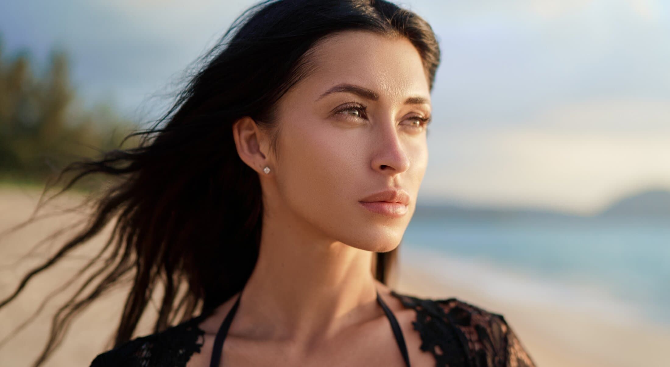 Woman with flowing hair on beach at sunset.