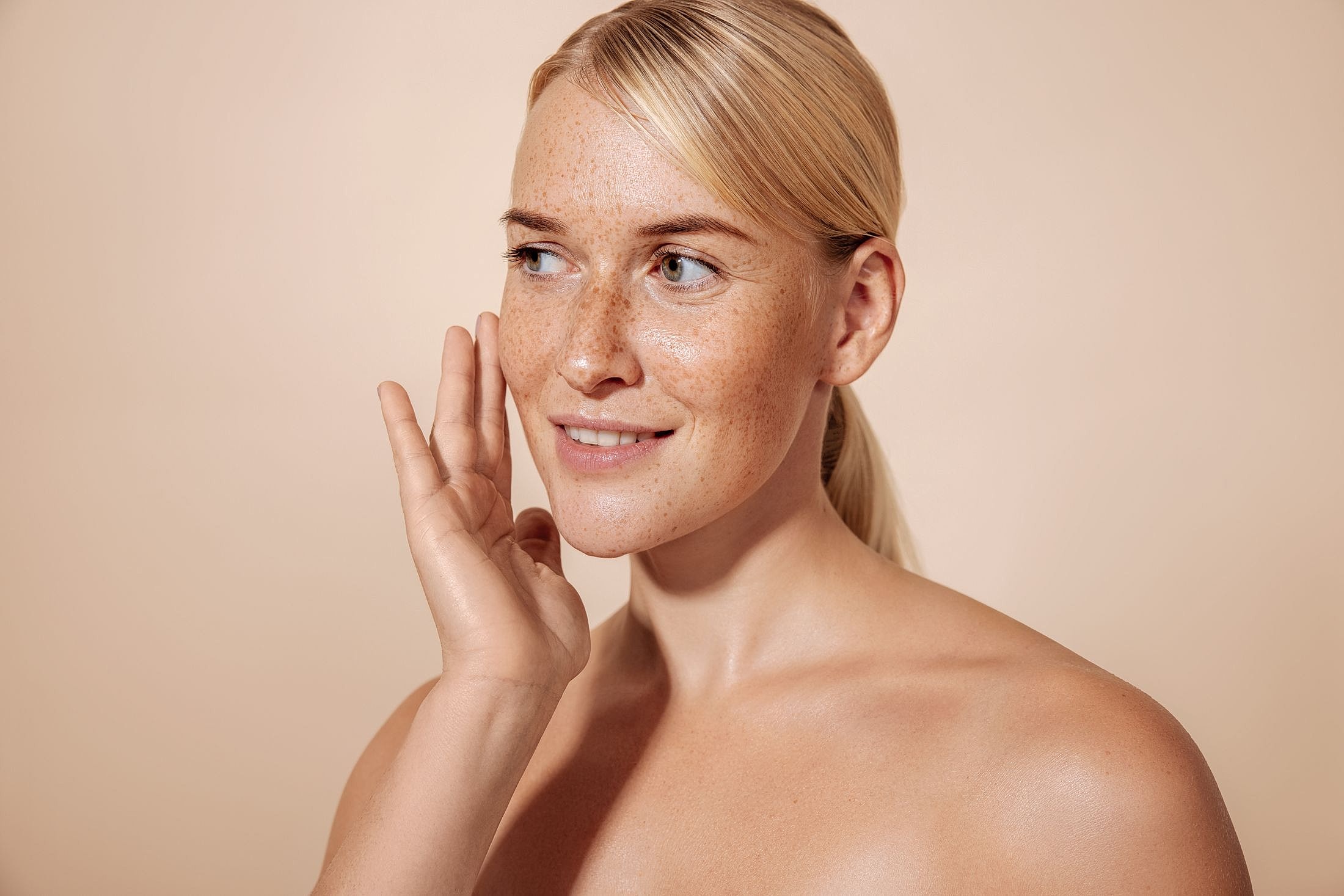 Smiling person with freckles against a neutral background