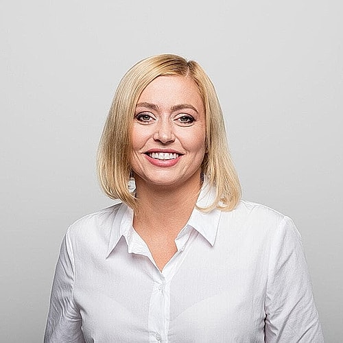 Smiling woman in white shirt against gray background.